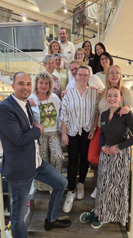 Das Team von Echter Wohnen auf der Treppe im Einrichtungshaus – Mitarbeitende aus Beratung, Service und Deko, die gemeinsam für Stil und Herzlichkeit stehen.