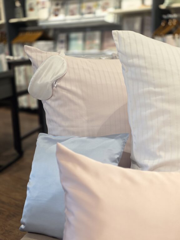 Kissen in Rosa, Hellblau und Weiß in weicher, eleganter Ausführung, und eine nette Schlafmaske in kuschelig weiß.