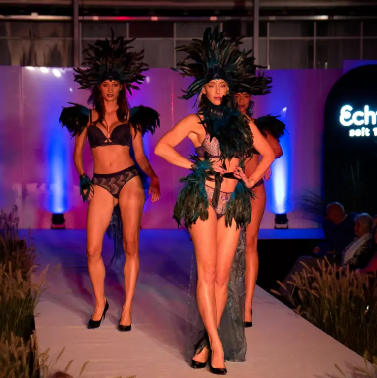 Drei Models in aufwendigen Dessous- und Feder-Outfits auf dem Laufsteg bei bei der Kiefl Ladies Night im Gartencenter in Gauting