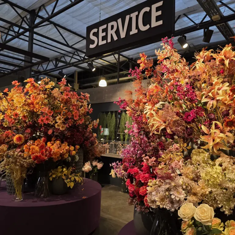 Üppige Blumenarrangements in leuchtenden Herbstfarben im Kiefl Gartencenter in Gauting. Das Schild Service hängt prominent oben.