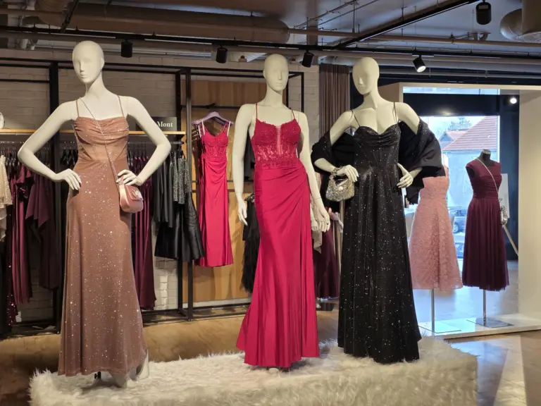 Die Anlassmode-Abteilung im Modehaus Echter in Weilheim. Im Vordergrund stehen drei schöne Puppen, die wunderschöne Kleider in beige, rot und schwarz mit Glitzer tragen. 