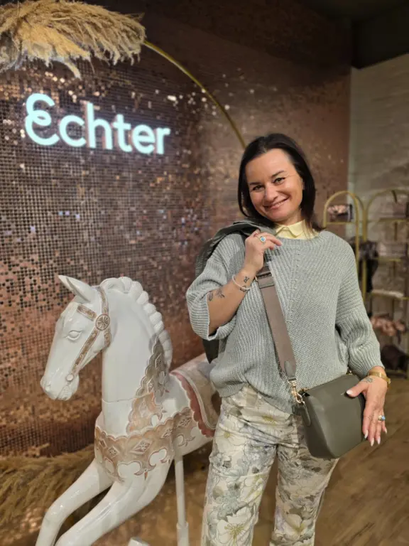 Modernes Damen-Outfit mit Tasche bei Echter Mode in Weilheim vor der Shimmerwall.