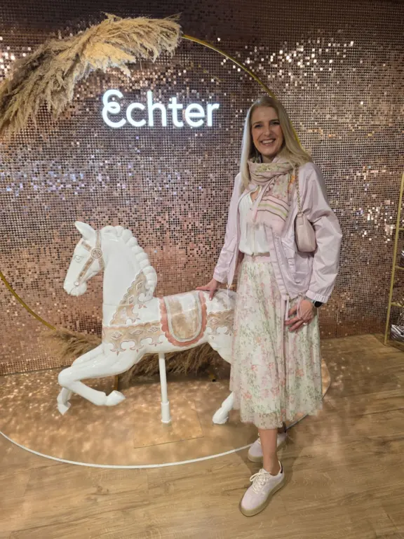 Model in einem Frühlingskleid mit Schal zeigt die Damenmode bei Echter Mode in Weilheim vor der Shimmerwall.