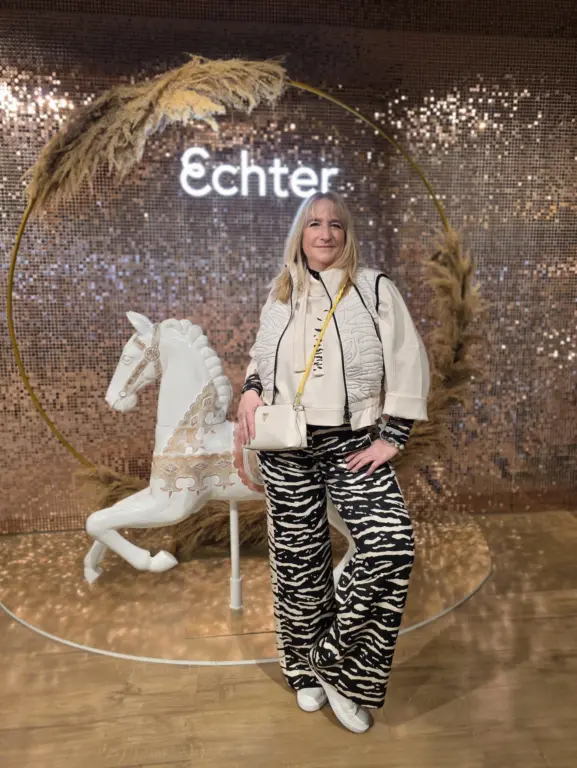 Modeberaterin mit Zebrahose und Crossbody-Bag bei Echter Mode in Weilheim vor der Shimmerwall.