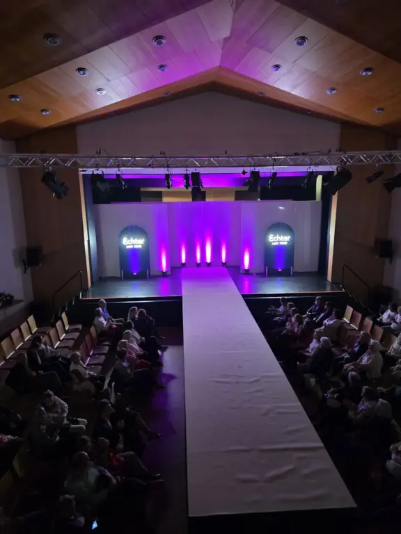 Blick auf den Laufsteg bei der Echter Mode Show in Kultur- und Tagungszentrum Murnau von oben mit schönen violetten Bühnenlichtern.