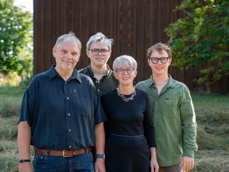 Familie Kiefl steht lächelnd im Grünen nebeneinander im Gartencenter in Gauting