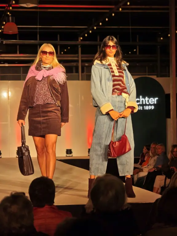 Zwei Models mit Sonnenbrillen in einem braunen Rocklook und einer hellblauen Hosenkombination.