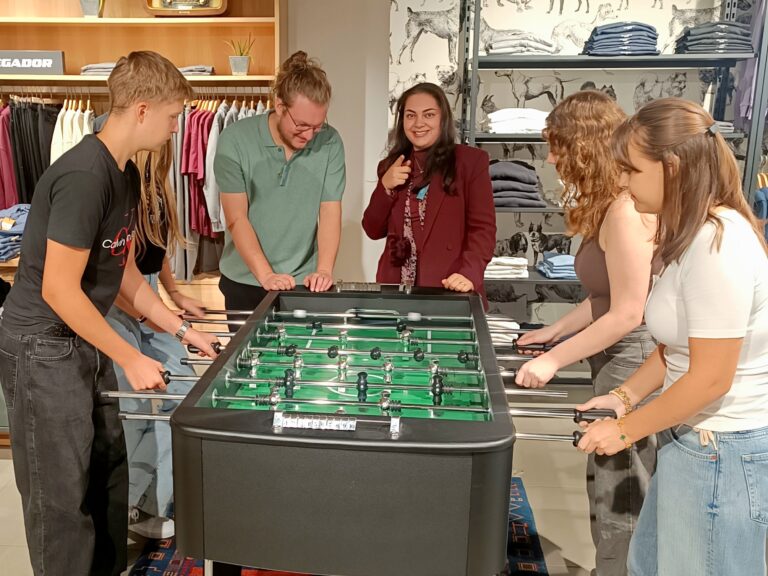 Neue Azubis spielen Kicker in der Herrenabteilung des Modehauses und haben Spaß