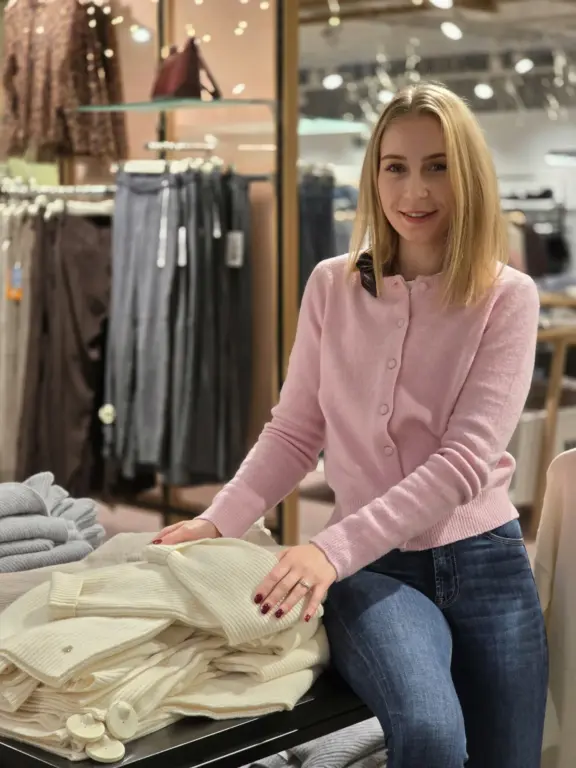 Sara aus Gauting präsentiert einen rosafarbenen Strickcardigan und helle Rippstrickteile.