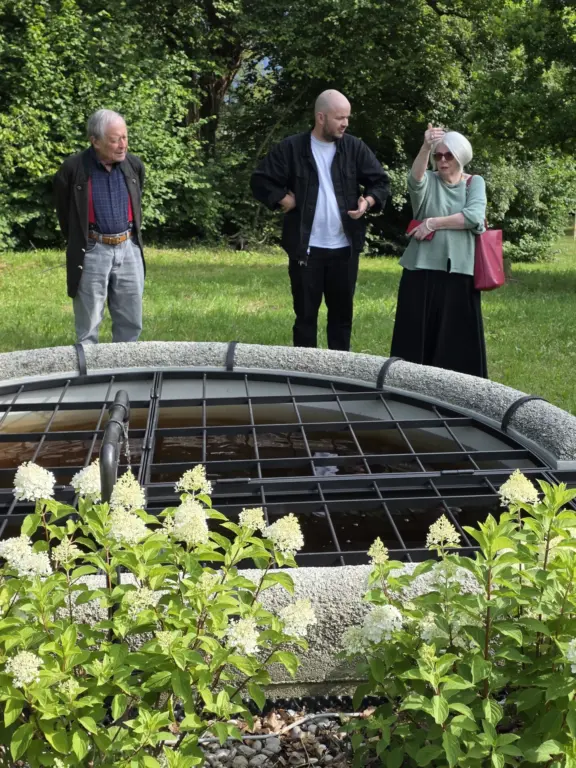 Drei Personen stehen hinter dem restaurierten Seidlbrunnen im Murnauer Seidlpark.