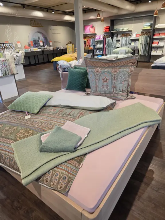 Dekoriertes Bett mit sommerlicher Bettwäsche, Tagesdecken und Kissen bei Echter Wohnen