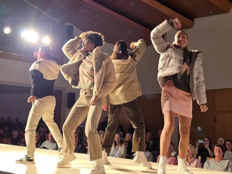 Tanzende Models auf dem Laufsteg bei der Großen Echter Modenschau in Murnau. Trendige Winterlooks mit Teddyjacken und sportlichen Styles.