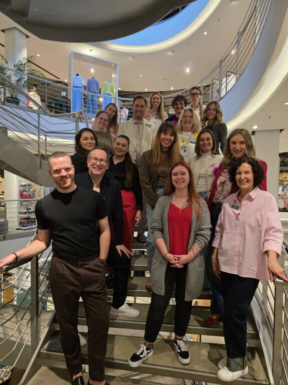 Das Team von Echter Mode und Wohnen im Haus Weilheim – Menschen aus verschiedenen Abteilungen gemeinsam auf der Treppe im Modehaus.