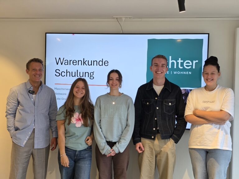 Fünf junge Menschen bei einer internen Warenkunde-Schulung bei Echter Mode und Wohnen – mit Produktmanager vor Präsentationswand.
