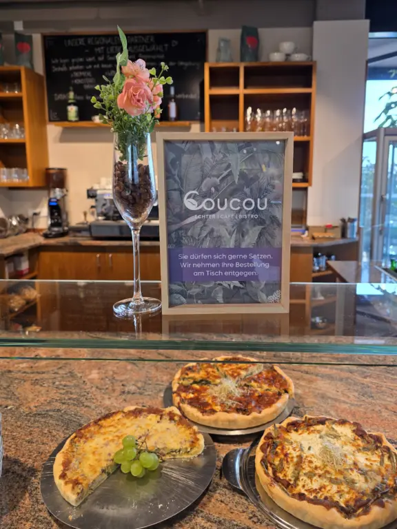 Cafe und Bistro Coucou im Echter Modegeschäft 2. OG in Weilheim mit hausgemachten Quiches, Pizza und Blumendekoration am Tresen.
