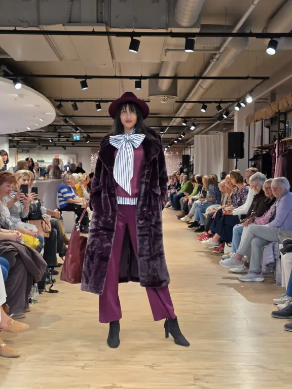 Mode mit Charakter und Retro-Charme. Model in violettem Samt-Outfit und Hut auf dem Laufsteg der Großen Echter Modenschau in Weilheim am 27.09.2025